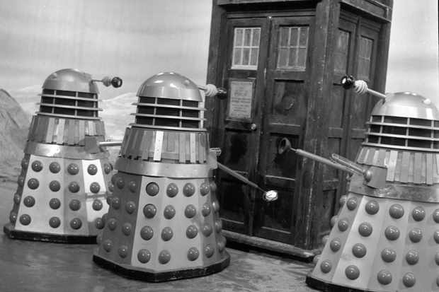 Screencap from The Chase: In a desert, three Daleks stand encircling the TARDIS.