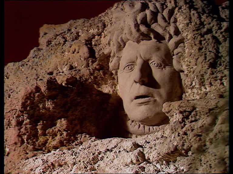 Screencap from The Face of Evil: Tom Baker (The Doctor)'s face carved into a huge mountainside.