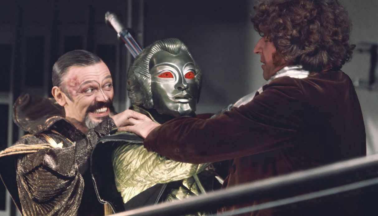 Screencap from The Robots of Death: The Doctor and a dark-haired man (Uvanov) struggle with a red-eyed robot between them.