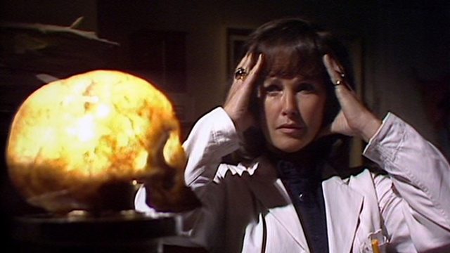 Screencap from Image of the Fendahl: a woman in a lab coat stares at a glowing skull, her hands held to her temples.